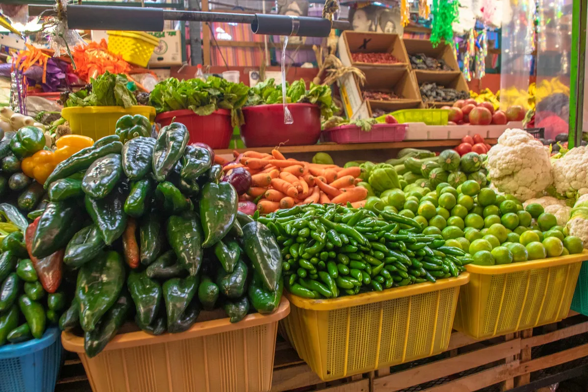 Baskets of poblano and serrano chiles, carrots and limes on a market stall
